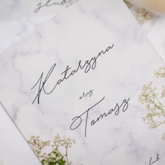 Piękne zaproszenie z&nbsp;gipsówką i&nbsp;motywem marmuru z&nbsp;białą kopertą i&nbsp;zieloną wstążką