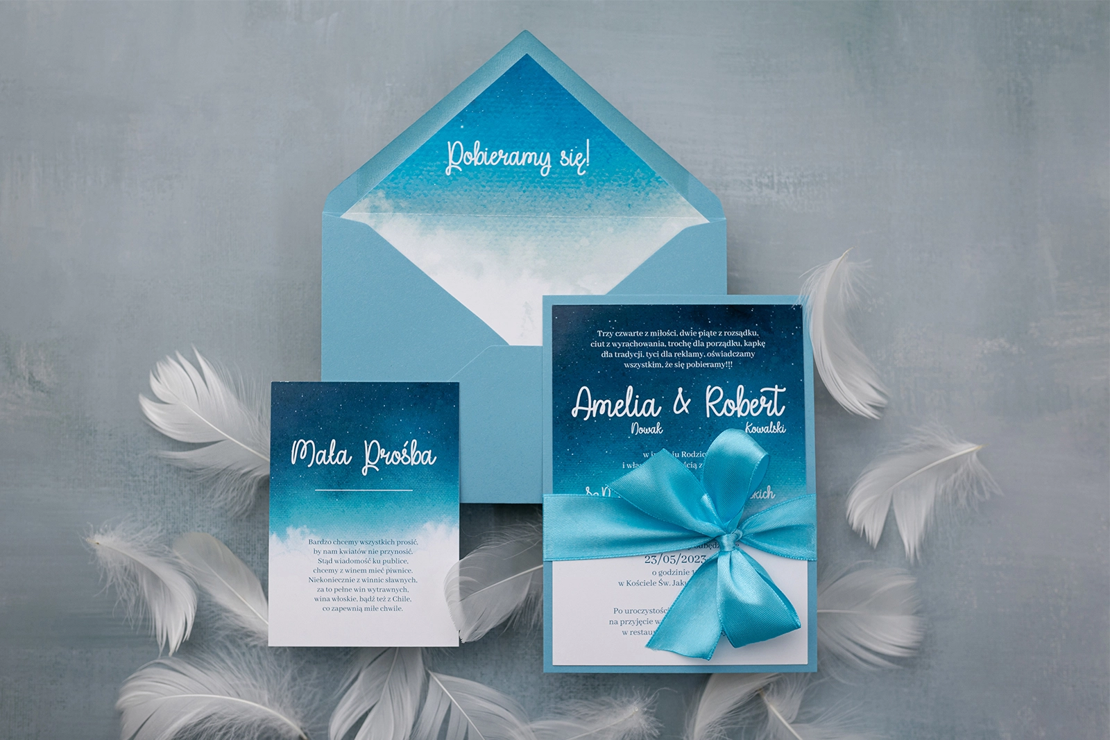 Zaproszenia ślubne Cloud w błękitnych barwach z kopertą i satynową kokardą